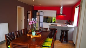 Una cocina moderna con una pared de acento roja, un comedor con sillas de madera y una mesa, y un horno empotrado.