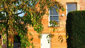 Un edificio de madera con una puerta blanca, una ventana y un muro de ladrillo.