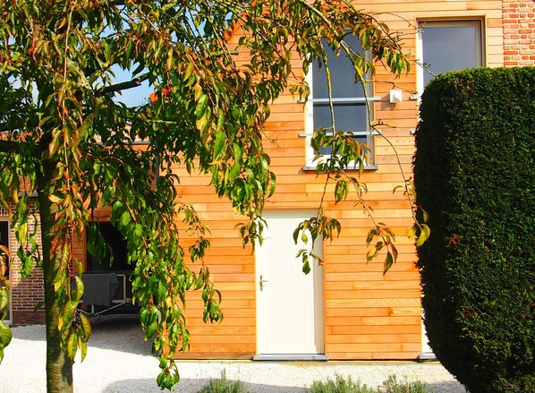A wooden building with a white door, a window, and a brick wall. - Spacious Home With Games (Ellezelles)