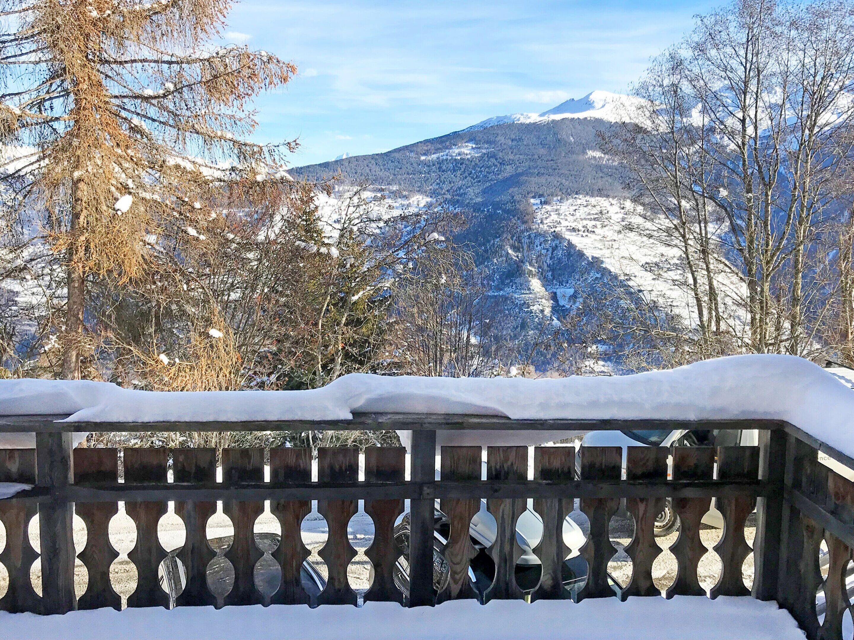A snow-covered balcony with a view of a mountain range.