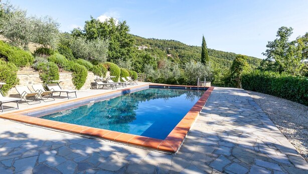 A rectangular swimming pool with a tiled edge, surrounded by stone tiles and a stone wall. - Villa in Lisciano Niccone With Pool & Nature (Lisciano Niccone)
