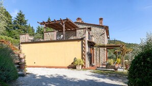 A stone house with a covered porch and a gravel driveway. - Villa in Lisciano Niccone With Pool & Nature (Lisciano Niccone)