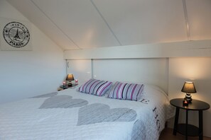 A bedroom with a bed, a nightstand, a lamp, a wall clock, and a wall decoration.