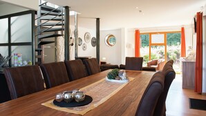 A modern dining area with a wooden table, leather chairs, a spiral staircase, and a view through large windows. - Holiday Home in Stoumont near Town of Spa (Stoumont)