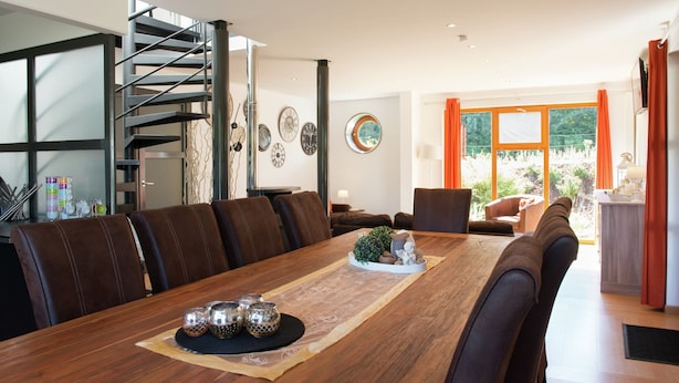 A modern dining area with a wooden table, leather chairs, a spiral staircase, and a view through large windows. - Holiday Home in Stoumont near Town of Spa (Stoumont)