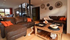 A modern living room with two brown leather sofas, a wooden coffee table, and a staircase leading to an upper level. - Holiday Home in Stoumont near Town of Spa (Stoumont)