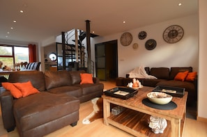 A modern living room with two brown leather sofas, a wooden coffee table, and a staircase leading to an upper level. - Holiday Home in Stoumont near Town of Spa (Stoumont)