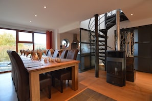 A dining area with a wooden table, chairs, and a spiral staircase.