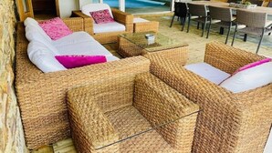 A cozy outdoor seating area with wicker furniture and a glass table, overlooking a pool and a green landscape. - Holiday Home in Stoumont near Town of Spa (Stoumont)