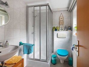 A bathroom with a glass shower enclosure, a sink, a toilet, and a mirror. - Pleasant Apartment in Bad Doberan near Sea (Bad Doberan)