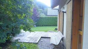 A wooden deck with a bench, a small table, and a hedge in a garden area. - Chalet in Saint-jean Near Ski Lift (Saint-Jean-d'Aulps)