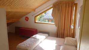A bedroom with a sloped ceiling, a window with curtains, a red bench, and a bed with white bedding. - Chalet in Saint-jean Near Ski Lift (Saint-Jean-d'Aulps)