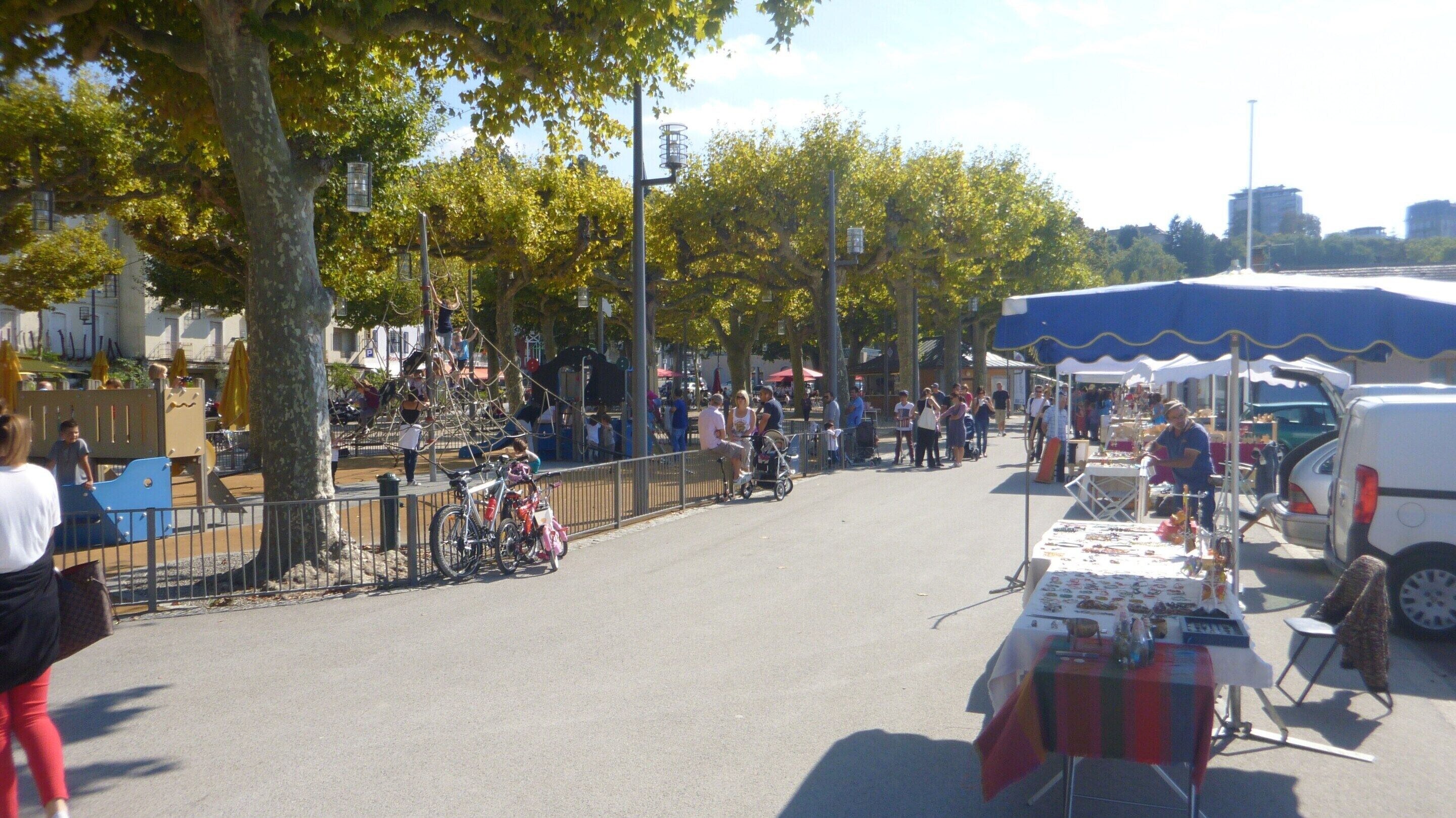 A street market with vendors, bicycles, and a playground.