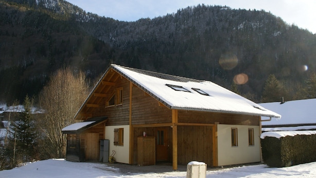 A wooden cabin with a snow-covered roof, a porch, and a view of a forested mountain. - Chalet in Saint-jean Near Ski Lift (Saint-Jean-d'Aulps)