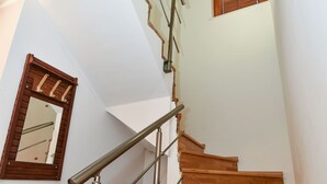 Una escalera de madera con barandillas metálicas y una puerta de madera con un espejo.