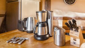 A kitchen with stainless steel appliances, including a coffee maker, a kettle, and a toaster. There is a clock on the wall and a knife block on the counter. - Historic Half Timbered Farm in Hohnebostel near Water Sports (Langlingen)