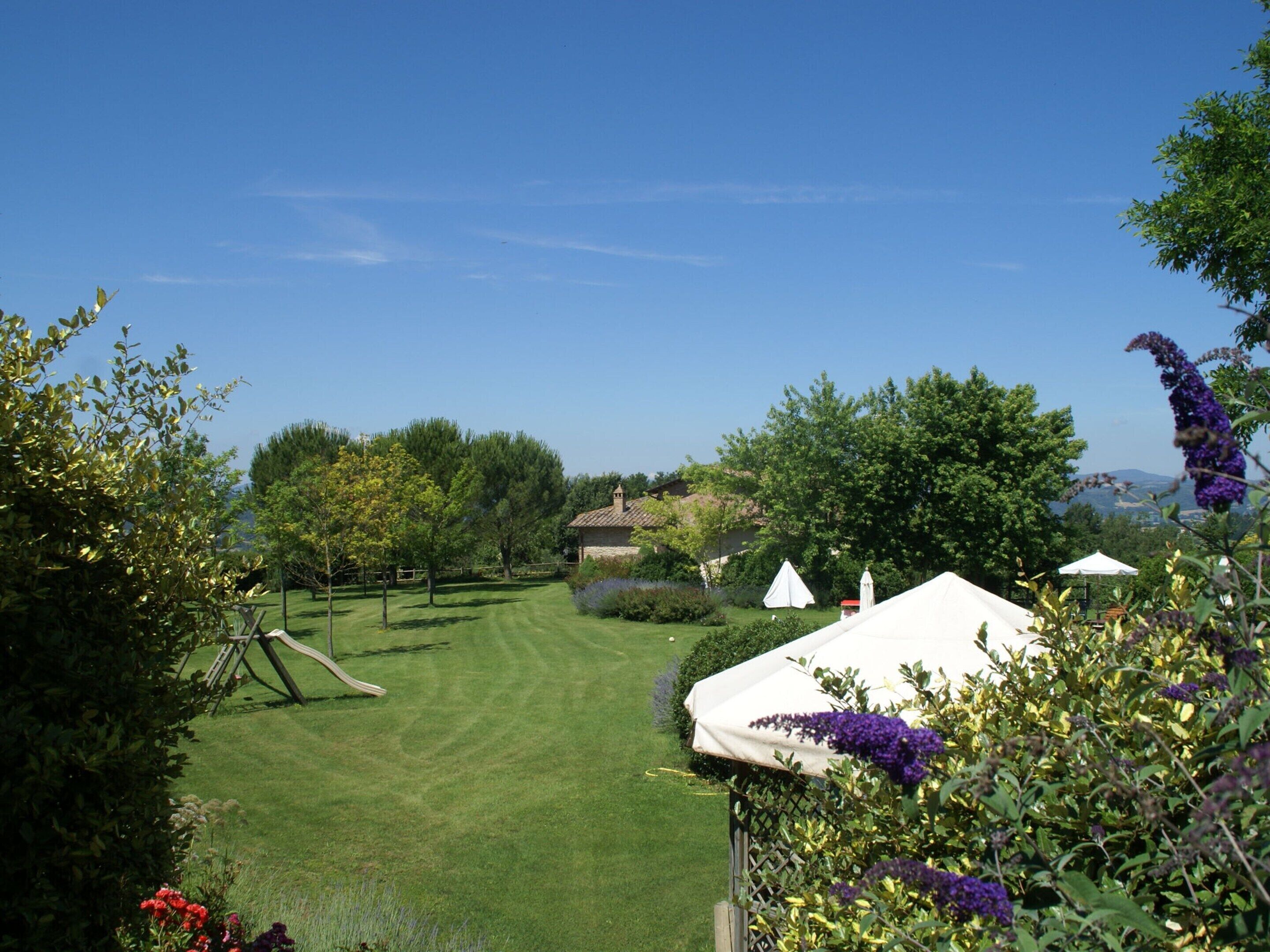 A well-maintained lawn with a small building, possibly a gazebo, and a white tent in the foreground.