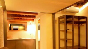 Ein kompakter Wohnraum mit Küchenzeile, Holzboden und integriertem Kleiderschrank.