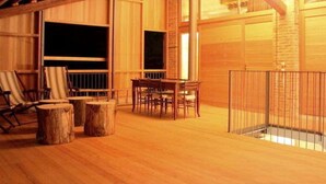 Ein gemütliches Holzinterieur mit Essbereich, großen Fenstern und einer Treppe zu einer oberen Ebene.