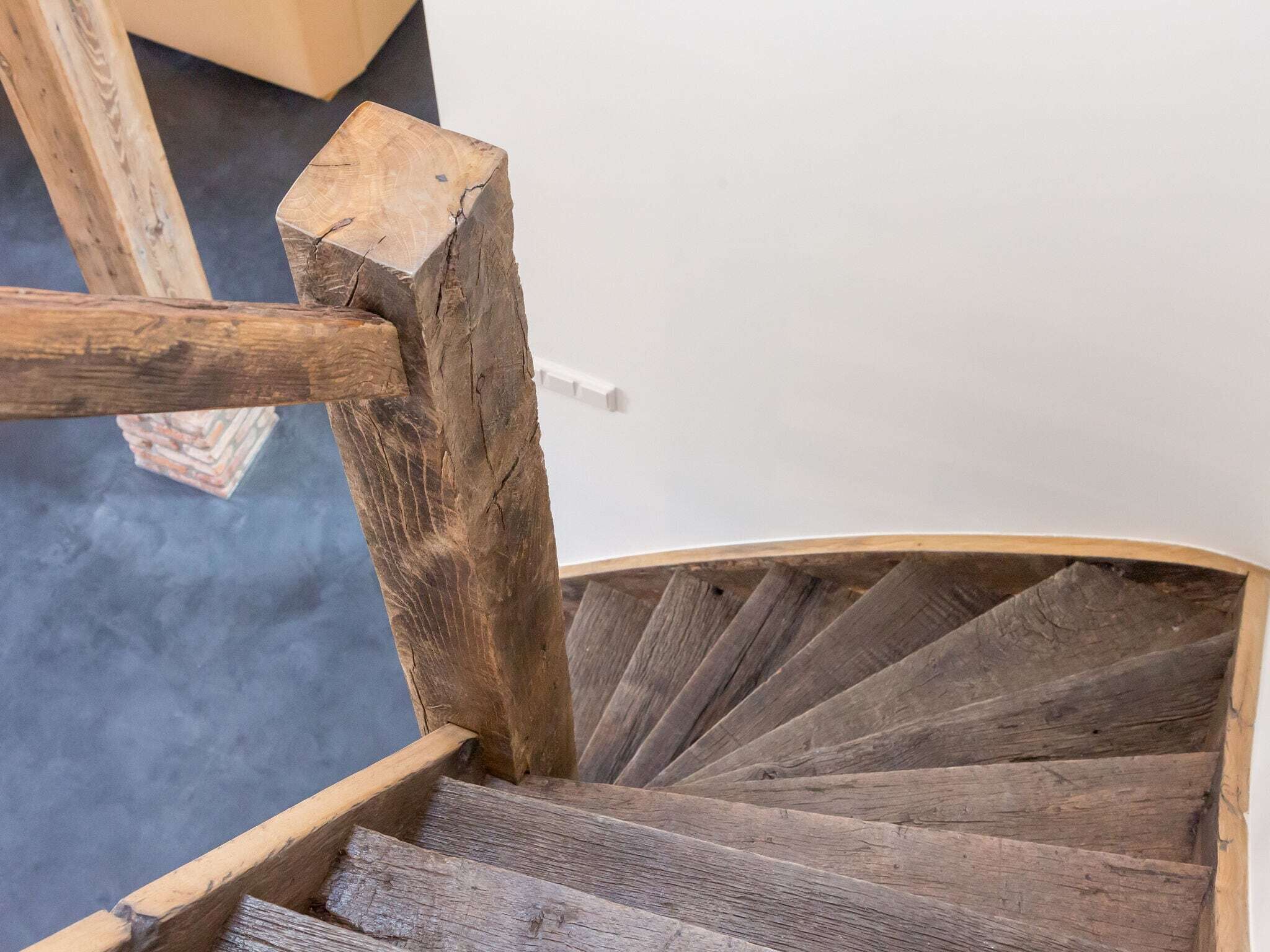 Un escalier en colimaçon en bois, doté d’une main courante et de marches.