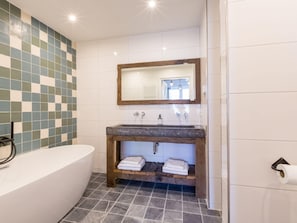A bathroom with a bathtub, a sink with a wooden vanity, and a mirror above the sink.