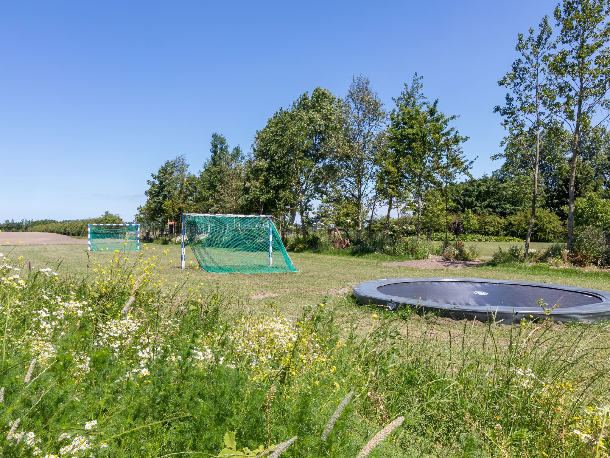 Un campo cubierto de césped con una portería de fútbol y un trampolín.