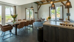 Een moderne keuken met een groot kookeiland, houten balken en hanglampen.