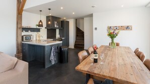 Een moderne keuken met een centraal eiland, een houten eettafel en een trap naar een hoger niveau.