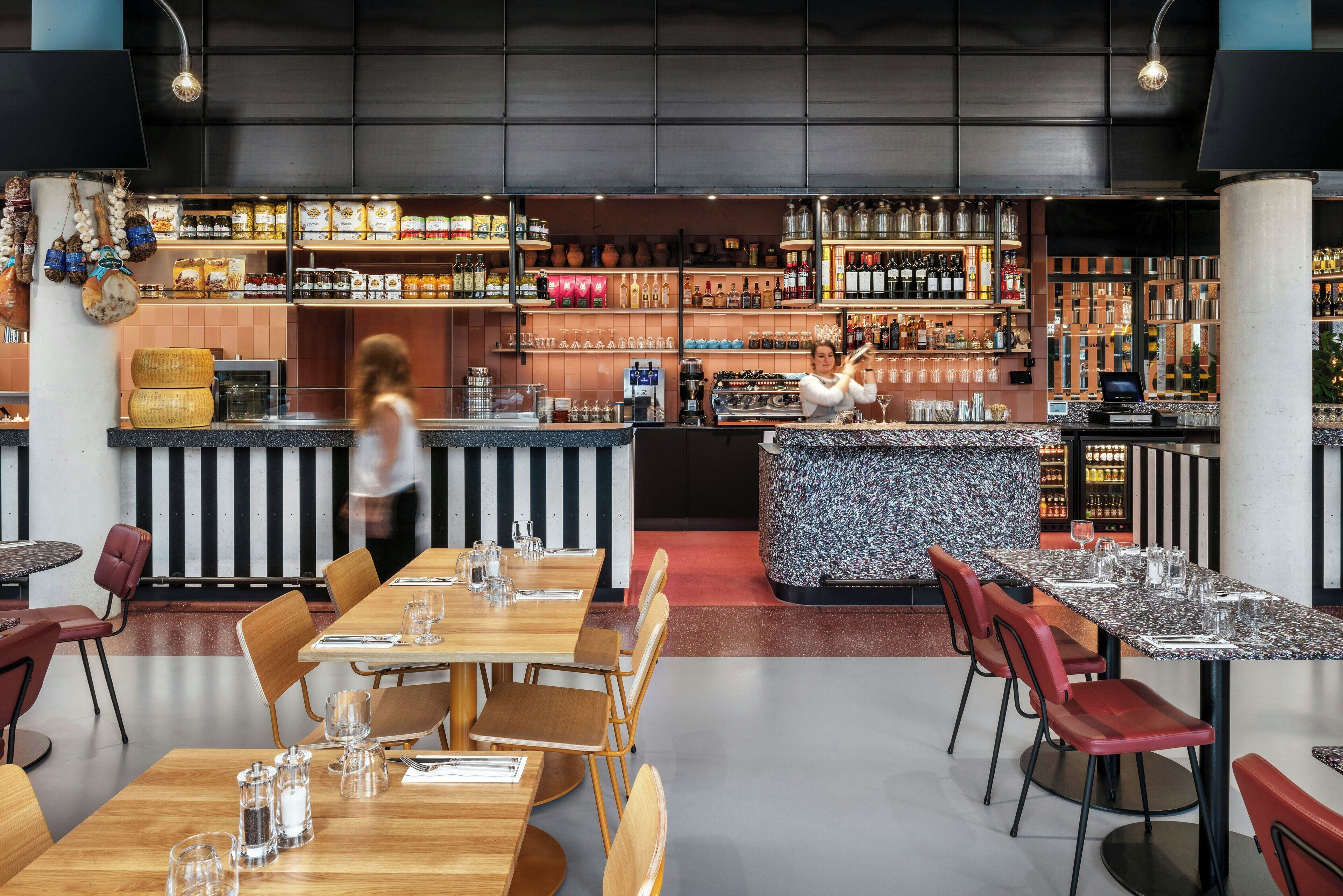A restaurant with a bar area, wooden tables, and chairs.