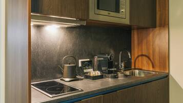 A modern kitchen with a built-in microwave, induction cooktop, coffee maker, and a sink.