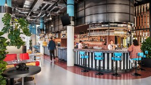 Un espace bar moderne avec un comptoir incurvé, des tabourets de bar bleus et une variété de bouteilles et de verres exposés sur des étagères.