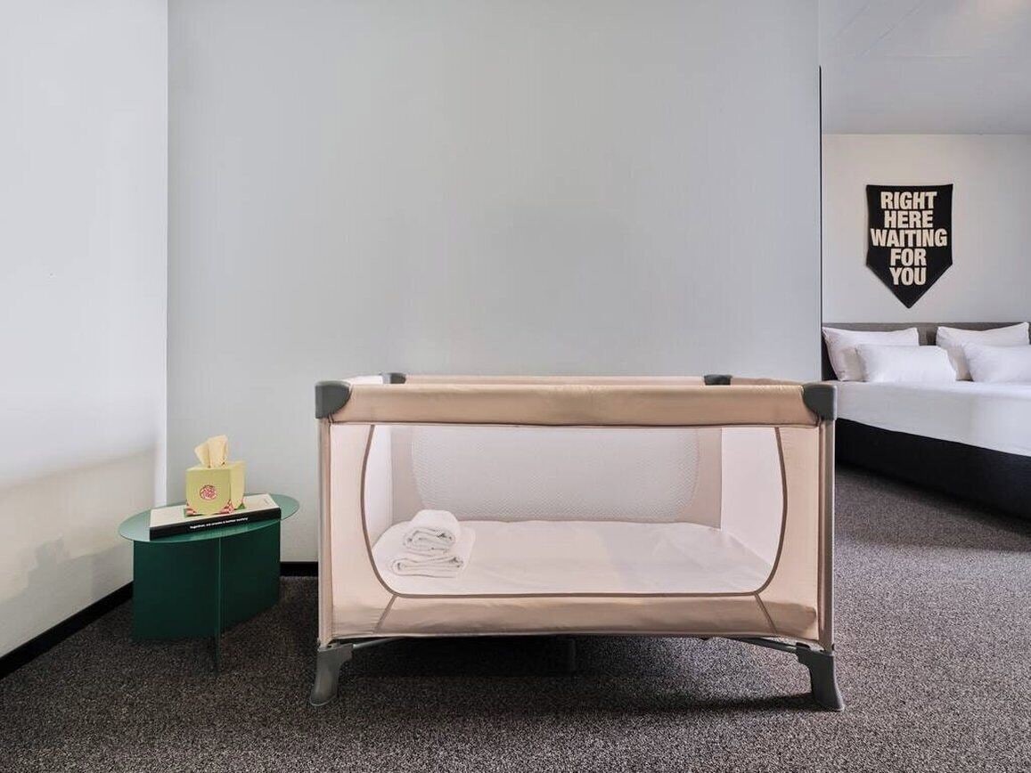 Una habitación con una cama individual, una mesita de noche pequeña con un dispensador de pañuelos de papel y un letrero en la pared.