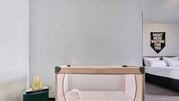 Una habitación con una cama individual, una mesita de noche pequeña con un dispensador de pañuelos de papel y un letrero en la pared.