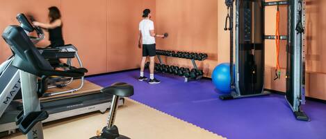 A gym with treadmills, dumbbells, and a weight machine.