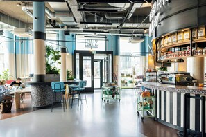 A modern interior with a bar area, seating, and a visible exit door. - The Social Hub Delft (Delft)