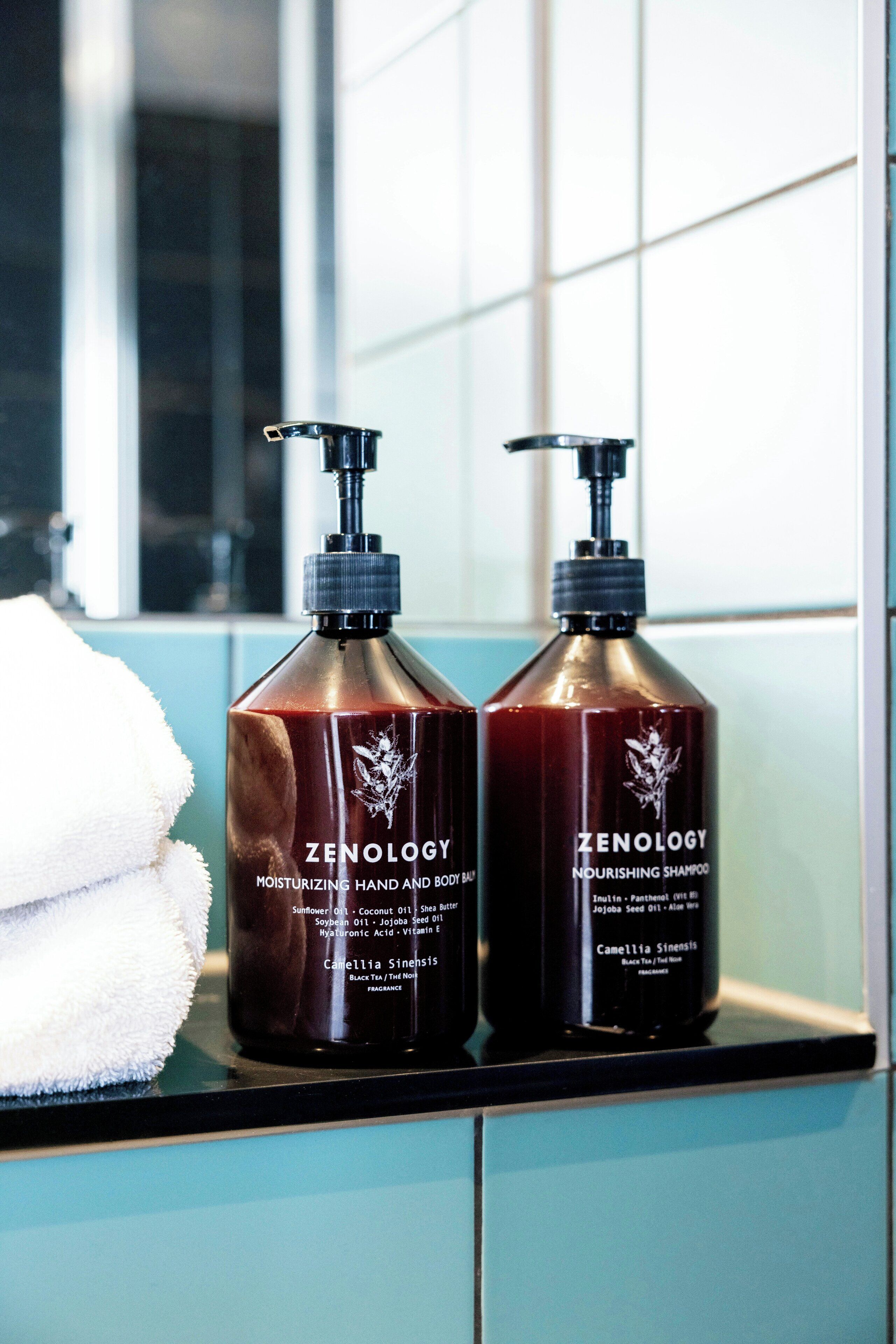 Two bottles of Zenology body and hair care products on a bathroom counter.