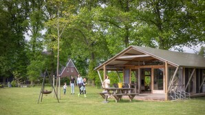 A wooden pavilion with a picnic table in a grassy area with trees. - Tent Lodge With Dishwasher in Twente (Haaksbergen)