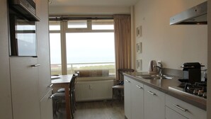 A compact kitchen with a dining area, large windows, and a view of the sea. - Cosy Apartment in Noordwijk aan Zee With Balcony (Noordwijk)