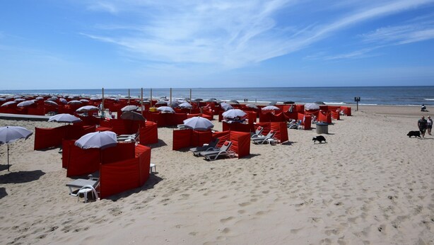 A beach with red umbrellas and lounge chairs arranged in rows. - Cosy Apartment in Noordwijk aan Zee With Balcony (Noordwijk)