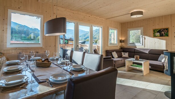 A wooden cabin interior with a dining area, sofa, and large windows offering mountain views. - Attractive Chalet With Whirlpool (Sankt Georgen am Kreischberg)
