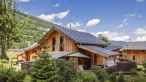 A wooden cabin with a sloped roof, solar panels, and a deck with outdoor furniture. - Attractive Chalet With Whirlpool (Sankt Georgen am Kreischberg)