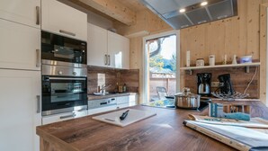 A modern kitchen with wooden cabinets, stainless steel appliances, and a wooden island with a cutting board and knife. - Attractive Chalet With Whirlpool (Sankt Georgen am Kreischberg)