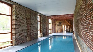 Una piscina interior con paredes de ladrillo y ventanas amplias.