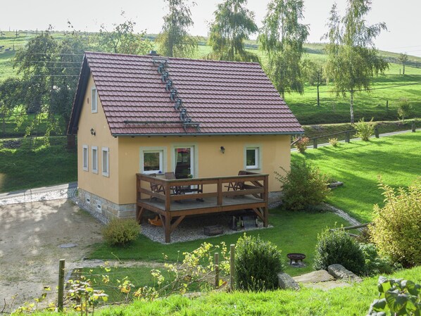 A two-story house with a red-tiled roof, a wooden deck, and a small garden area. - Sachsischer Wald Ruckzug (Hohnstein)