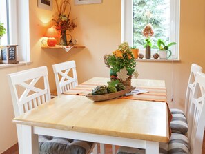 A dining table with chairs, a vase with flowers, and a bowl of vegetables. - Sachsischer Wald Ruckzug (Hohnstein)