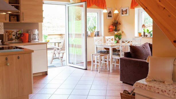 A cozy kitchen with a dining area, a sofa, and a staircase leading to an upper level. - Sachsischer Wald Ruckzug (Hohnstein)