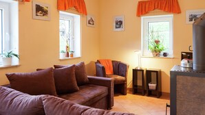 A cozy living room with a brown sofa, a small table, and a fireplace. - Sachsischer Wald Ruckzug (Hohnstein)