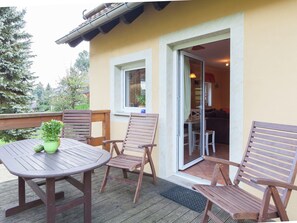 A patio with a table and chairs, a potted plant, and a view of the interior through a glass door. - Sachsischer Wald Ruckzug (Hohnstein)