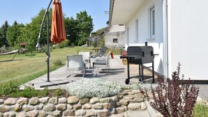An outdoor patio with a grill, seating, and a stone wall. - Ferienhaus vor den Toren der Insel Poel (Hornstorf)