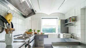 A modern kitchen with stainless steel appliances, a large window, and a built-in bookshelf. - Gruppenhaus im Harz (Bad Harzburg)